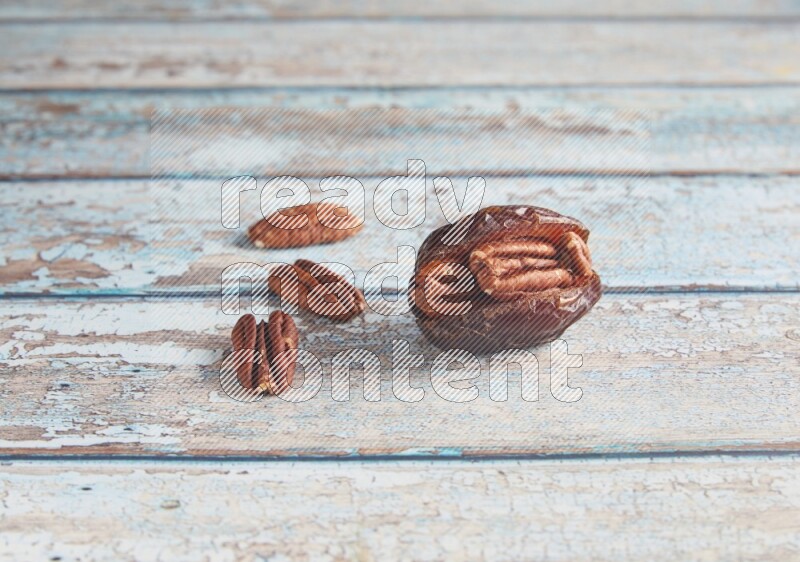 pecan stuffed madjoul date on a light blue wooden background
