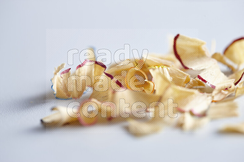 A close-up showing a small pile of pencil shavings with varied color edges on grey background