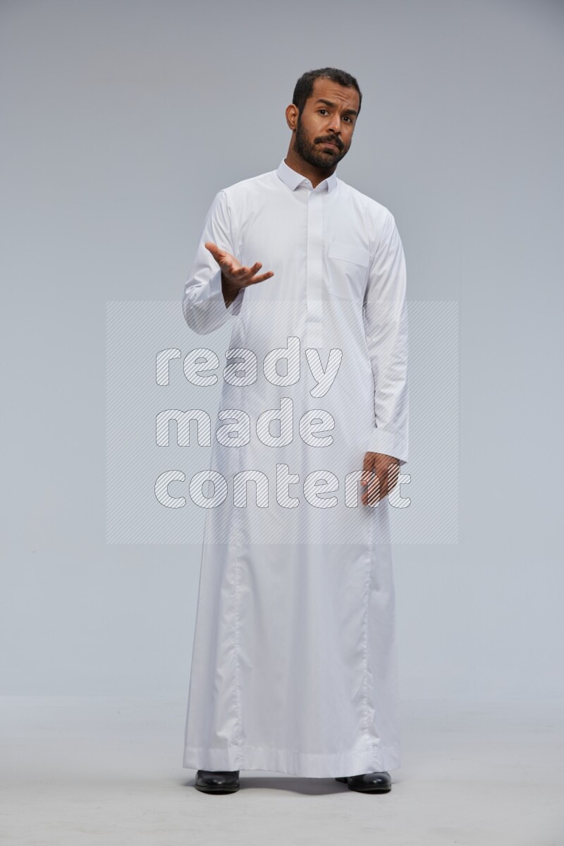 Saudi man Wearing Thob standing interacting with the camera on Gray background