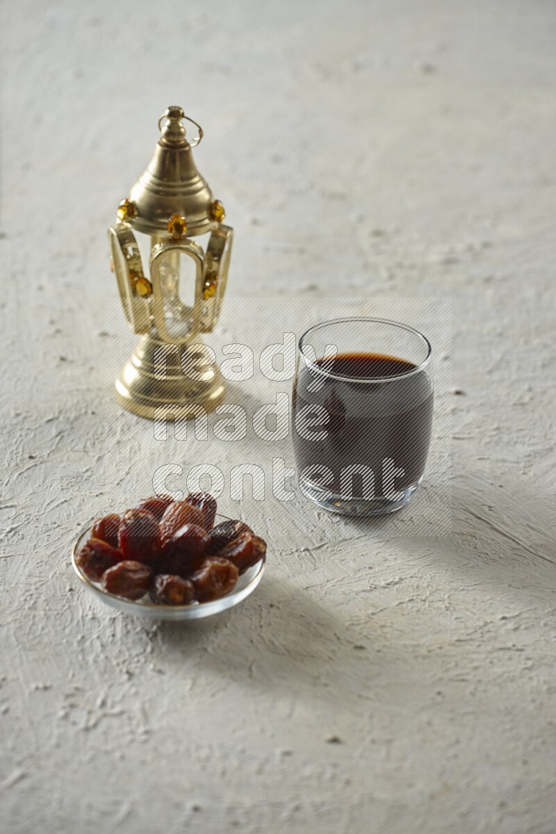 A golden lantern with different drinks, dates, nuts, prayer beads and quran on textured white background