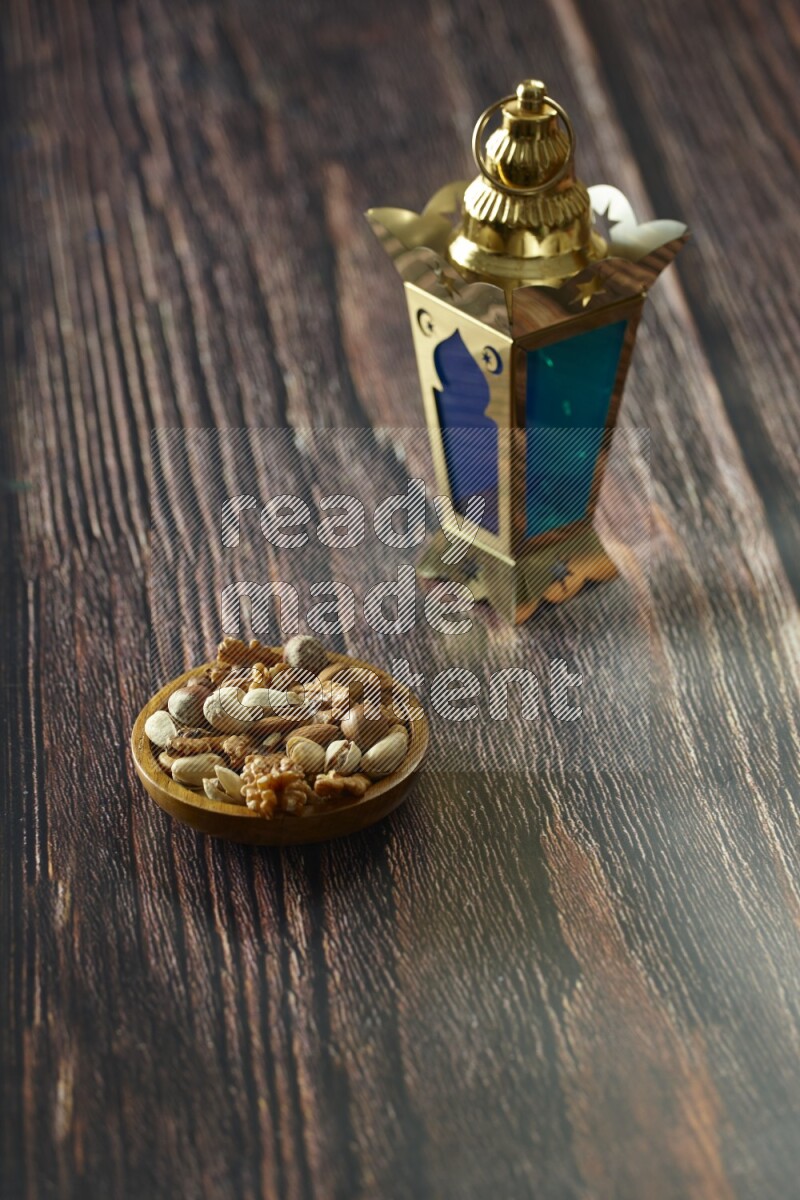 A golden lantern with different drinks, dates, nuts, prayer beads and quran on brown wooden background