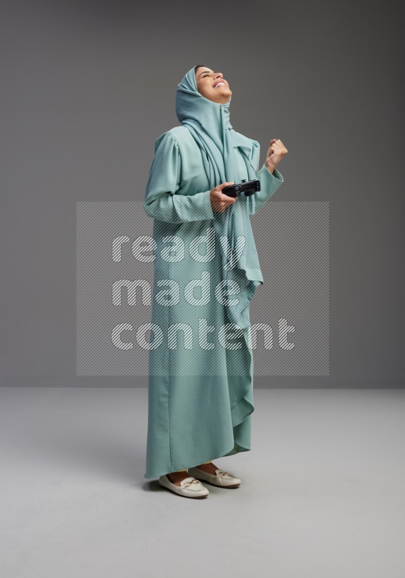 Saudi Woman wearing Abaya standing Playing Games on Gray background