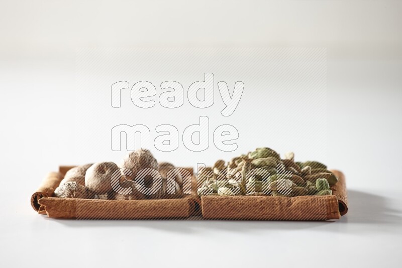 2 squares of cinnamon sticks full of cardamom and nutmegs on white flooring