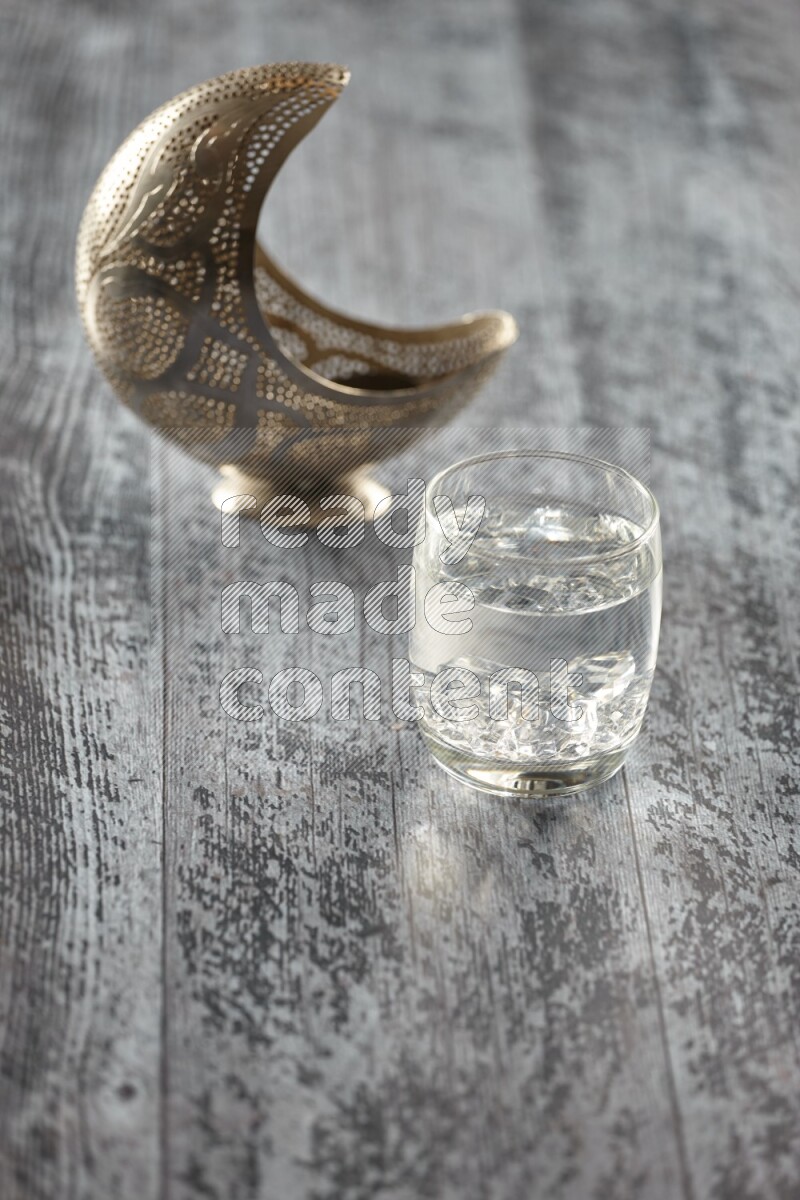 A silver lantern with different drinks, dates, nuts, prayer beads and quran on grey wooden background