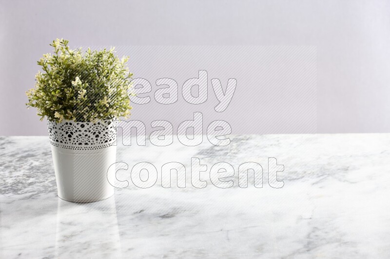 Artificial plant in white decorative pot on grey marble background