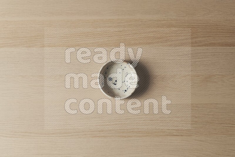 وعاء فخاري متعدد الألوان على خلفية خشبية فاتحة