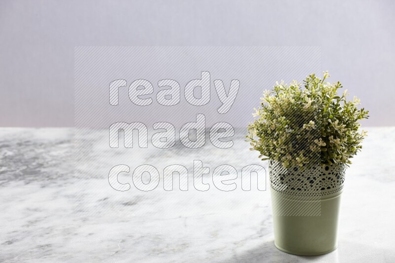 Artificial plant in green decorative pot on grey marble background