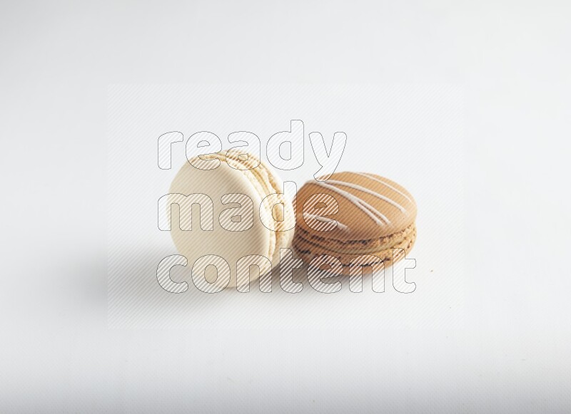 45º Shot of of two assorted Brown Irish Cream, and White Caramel fleur de sel macarons on white background