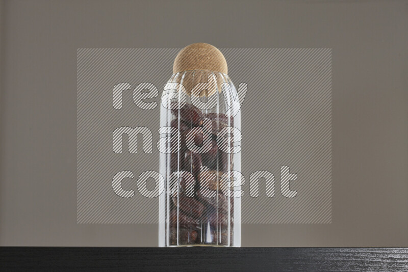 Dates in a glass jar on black background