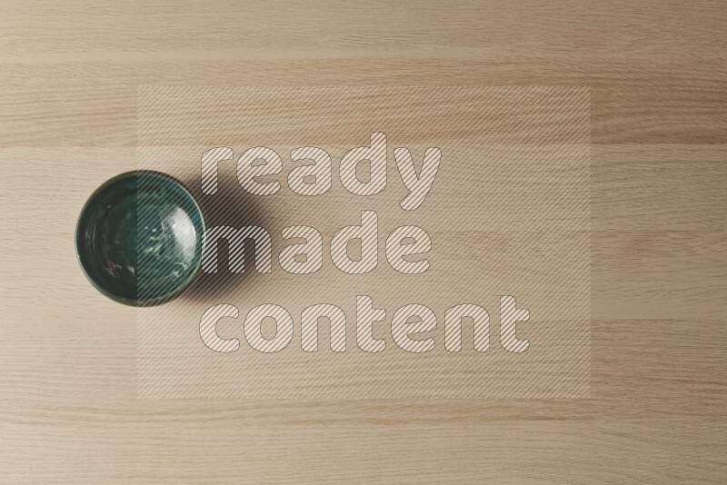 A dark green pottery bowl on light wooden background