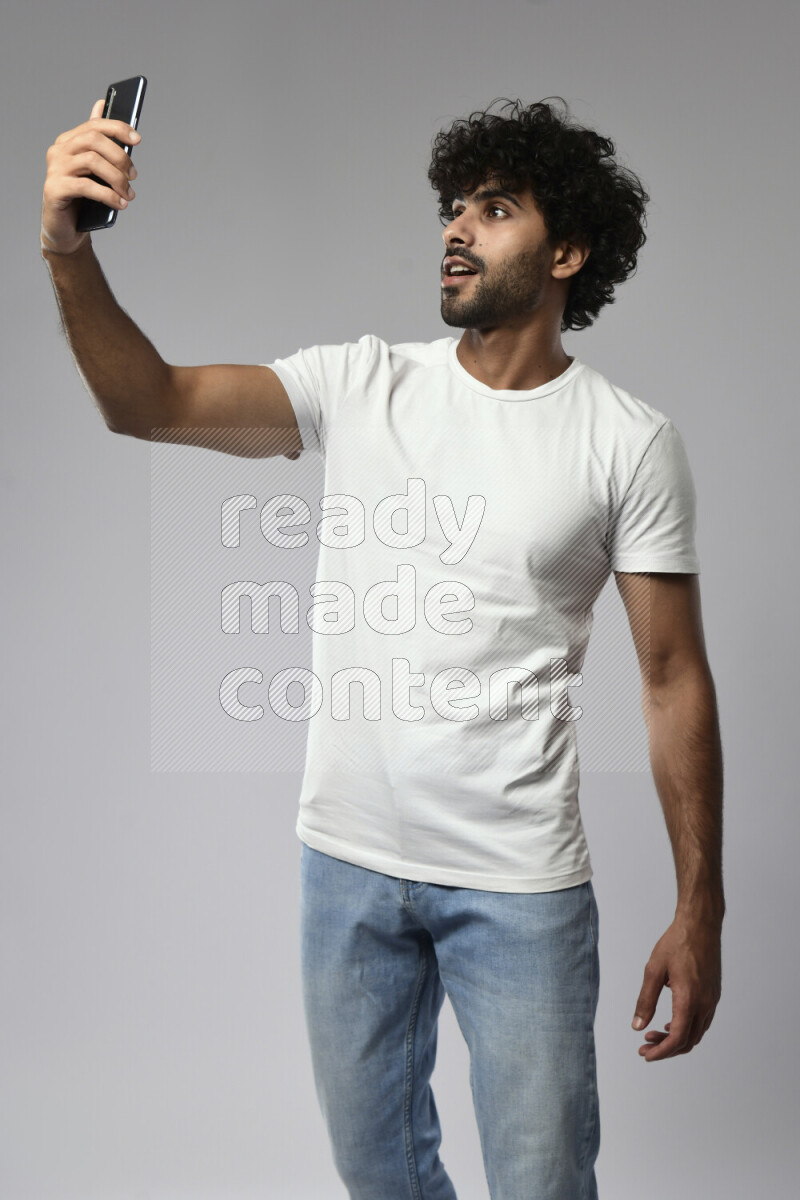 A man wearing casual standing and taking a selfie on white background