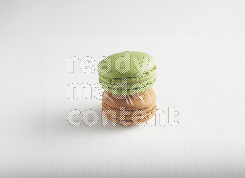 45º Shot of of two assorted Brown Irish Cream, and Green Pistachio macarons on white background