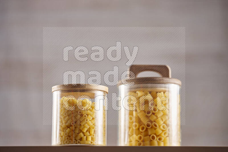Raw pasta in glass jars on beige background
