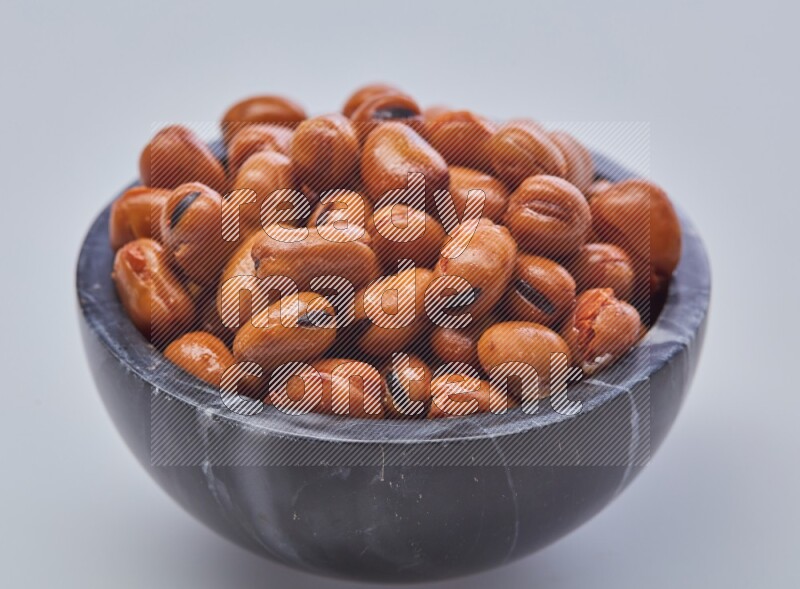 Close up shot of cooked fava beans (foul) in a container on white background