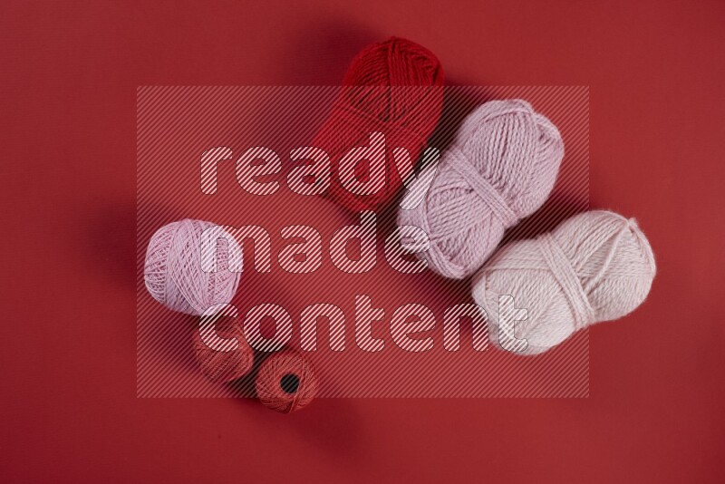 مجموعة من أدوات الخياطة والتفصيل زهرية وحمراء اللون على خلفية حمراء