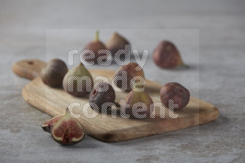 Fresh Figs on a wooden board on a textured grey background