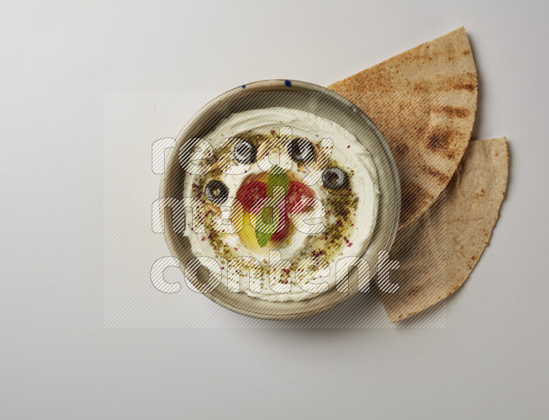 Lebnah garnished with cherry tomato, mint, olives & pine nuts in a grey pottery plate on a white background