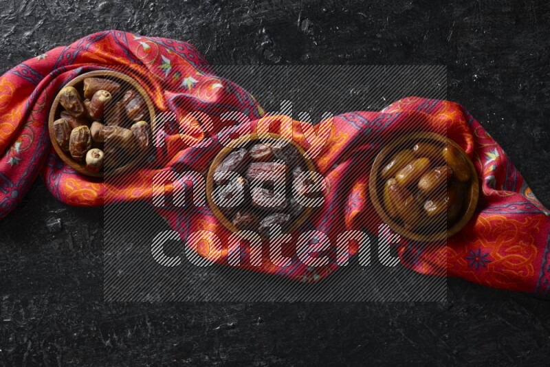Dates in wooden bowls in a dark setup