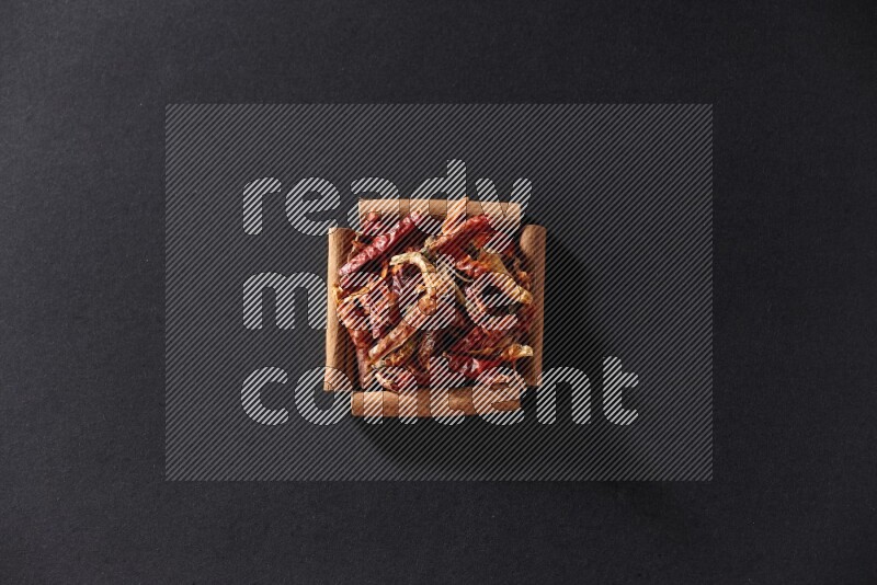 A single square of cinnamon sticks full of chilis on black flooring
