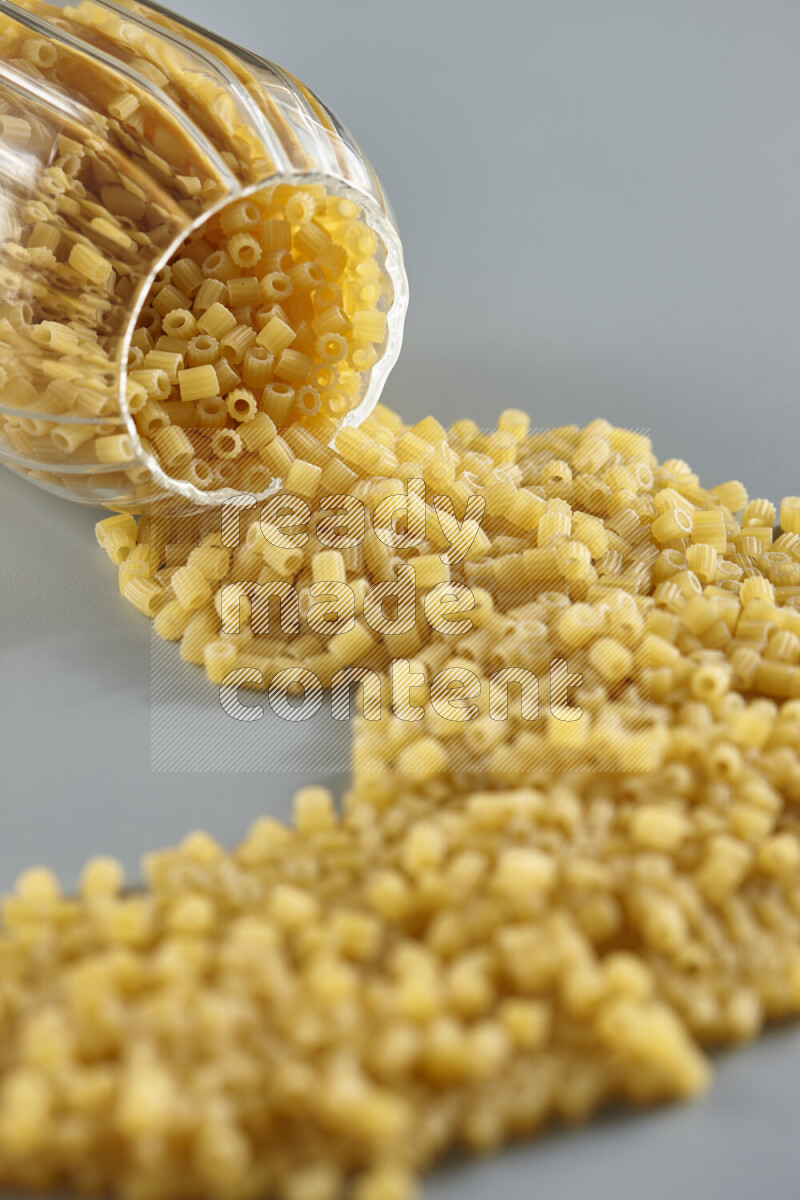 Flipped jar full of raw pasta on light blue background