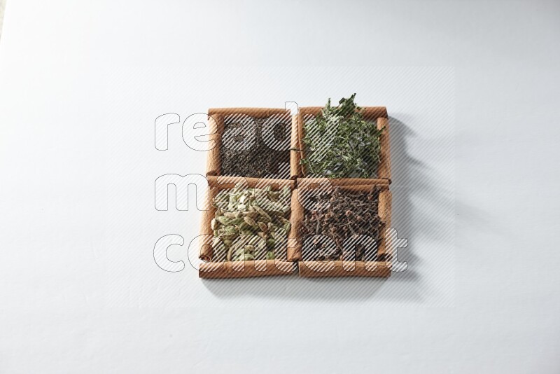 4 squares of cinnamon sticks full of tea, cardamom, mint and cloves on white flooring