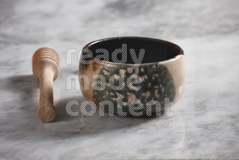 Multicolored pottery bowl with wooden honey dipper on the side on grey marble background