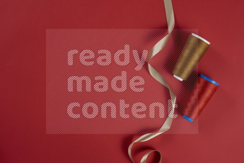 A brown and red collection of sewing and tailoring tools arranged on a red background