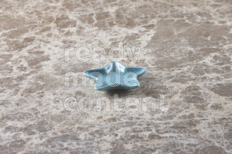 صحن فخاري ملون على شكل نجمه على خلفية من الرخام باللون البيج