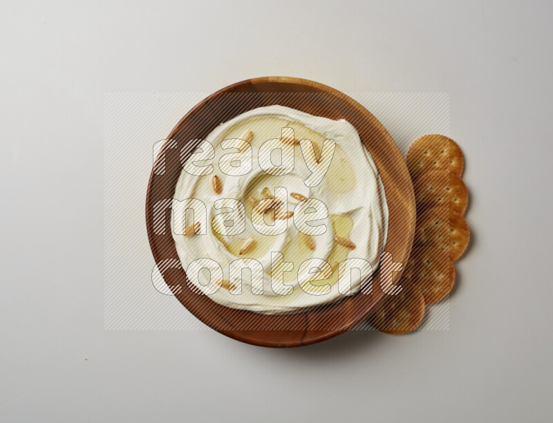 Lebnah garnished with pine nuts in a wooden plate on a white background