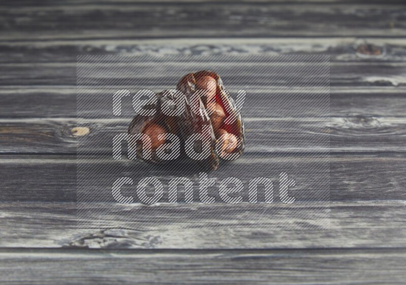 two hazelnut stuffed madjoul dates on a wooden grey background