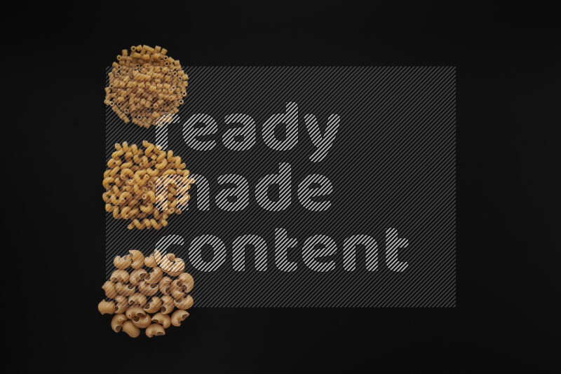 Different pasta types in 3 bunches on black background