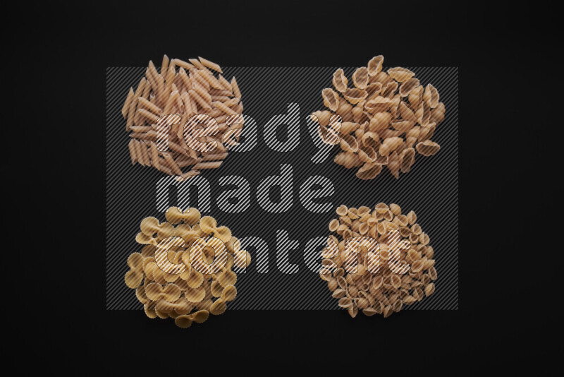 Different pasta types in bunches on black background