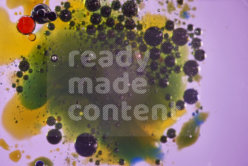 لقطات مقربة لقطرات ألوان مائية حمراء وزرقاء وصفراء وخضراء على سطح الزيت على خلفية وردية