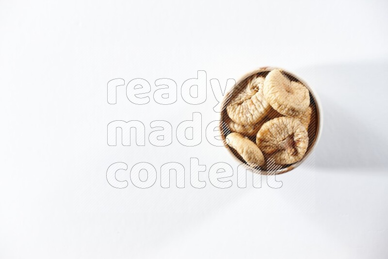 A beige ceramic bowl full of dried figs on a white background in different angles