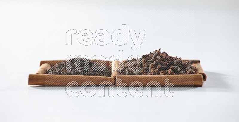 2 squares of cinnamon sticks full of black tea and cloves on white flooring
