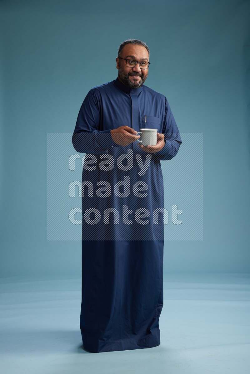 Saudi Man without shimag Standing drinking coffee on blue background