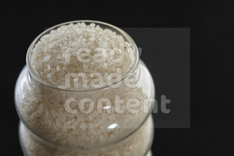 White rice in a glass jar on black background