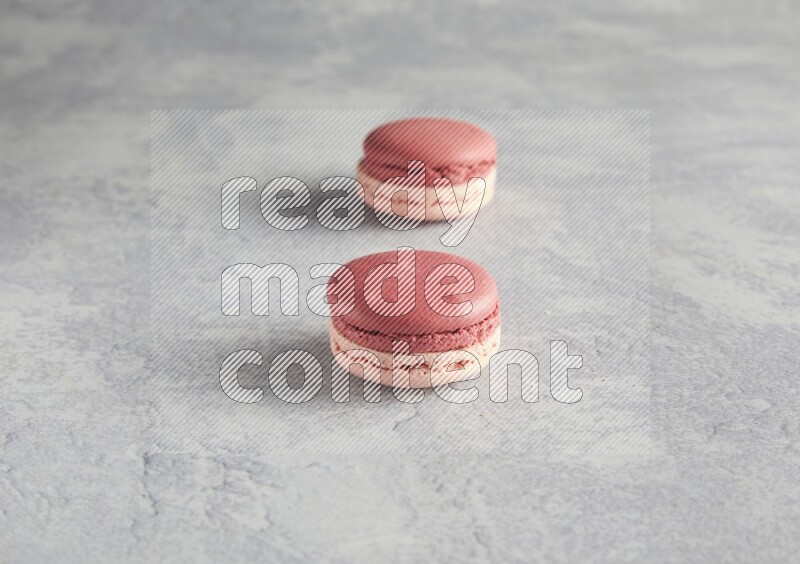 45º Shot of two Pink Litchi Raspberry macarons  on white  marble background