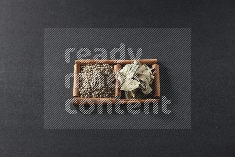 2 squares of cinnamon sticks full of white peppers and bay laurel leaves on black flooring