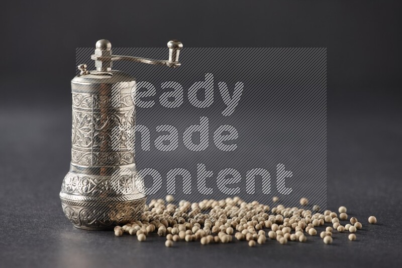 فلفل أبيض مع مطحنة فلفل معدنية على أرضية سوداء