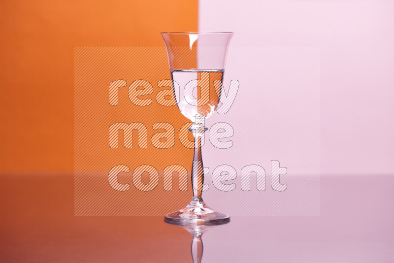 The image features a clear glassware filled with water, set against orange and rose background
