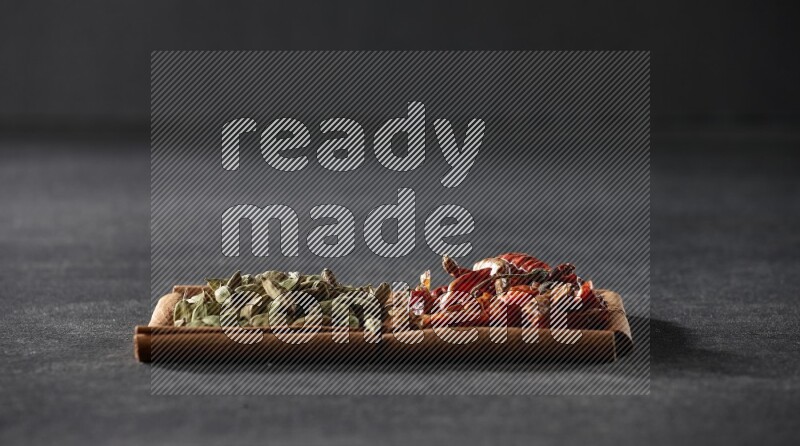 مربعان من أعواد القرفة ممتلئان بالفلفل الحار المجفف وحبوب الهيل علي خلفية سوداء