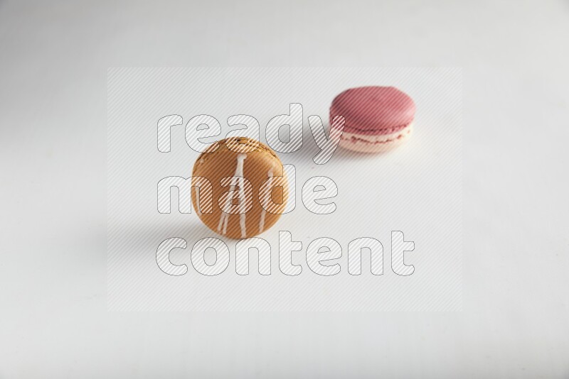 45º Shot of of two assorted Brown Irish Cream, and Pink Litchi Raspberry macarons on white background