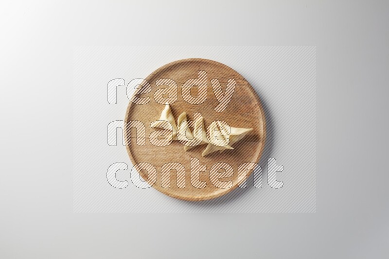 Five Sambosas on a wooden round plate on a white background