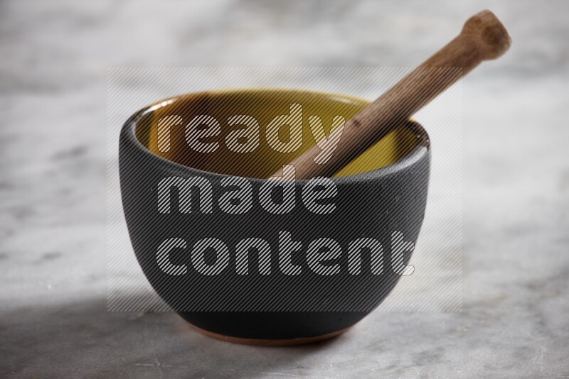 Multicolored pottery bowl with wooden honey dipper in it on grey marble background