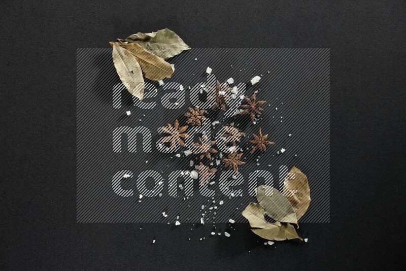 Salt, star anise and bay laurel on black flooring