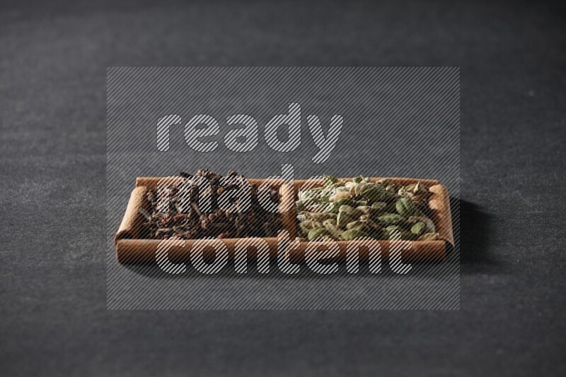 2 squares of cinnamon sticks full of cardamom and cloves on black flooring