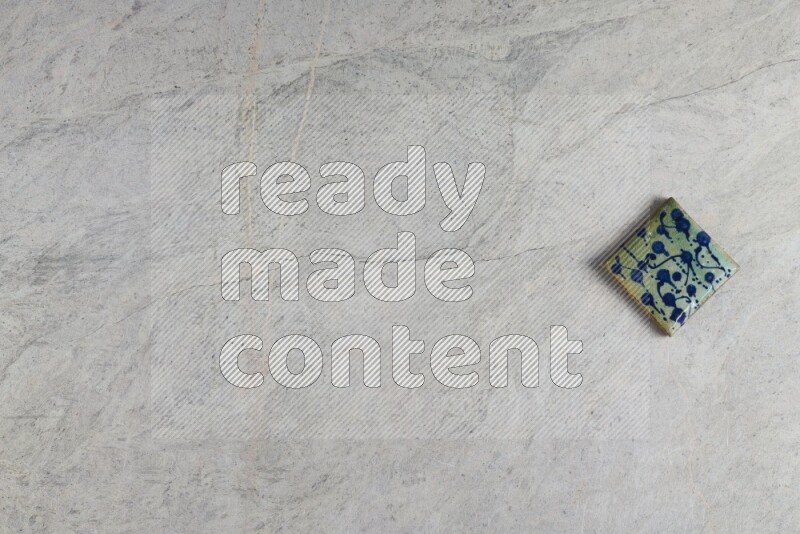 A decorative pottery coaster on grey marble background