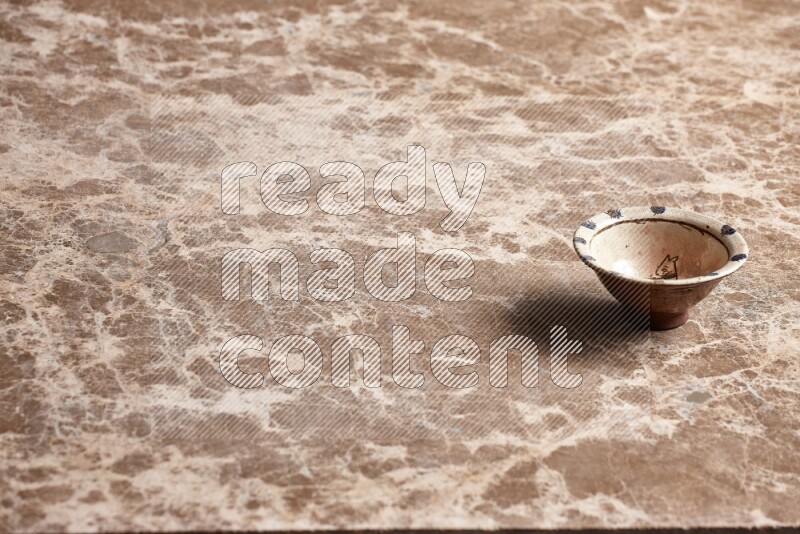 A decorative pottery bowl on beige marble background
