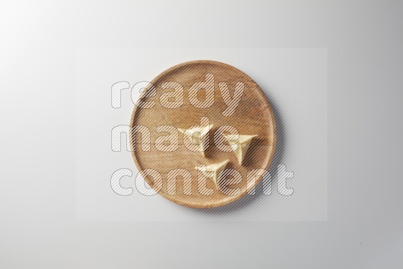Three Sambosas on a wooden round plate on a white background